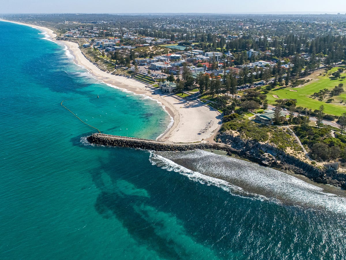Vista aérea de la costa de Perth, Australia, con una playa de agua cristalina turquesa y arena blanca.