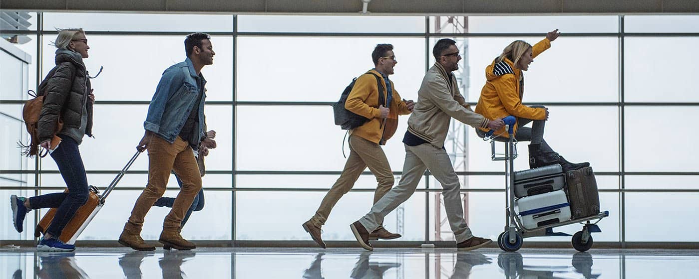 Groupe de voyageurs dans un aéroport qui poussent leurs valises 