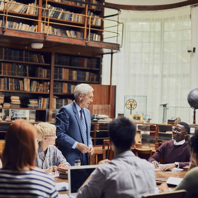 étudiants assis dans une bibliothèque autour d'un conférencier