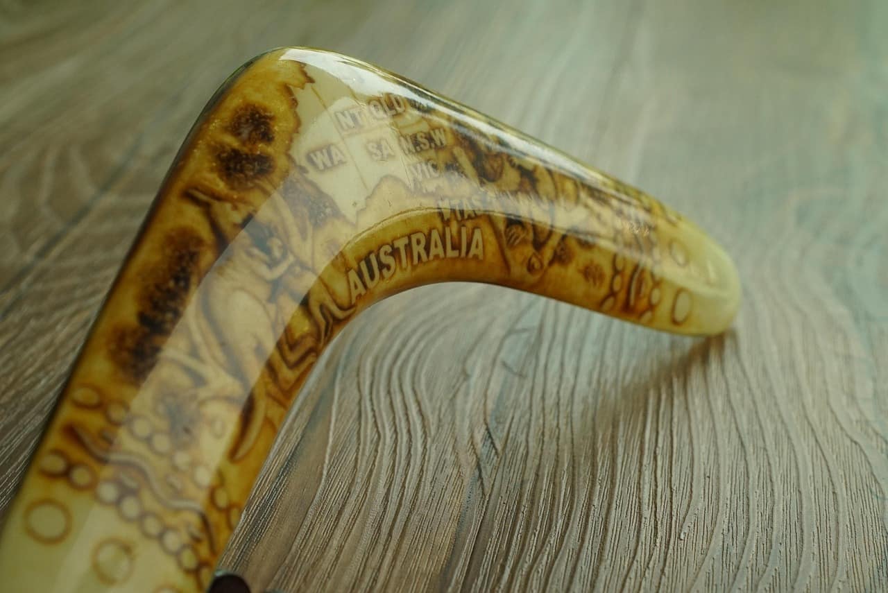 Boomerang artesanal con grabados y la palabra “Australia”, sobre una superficie de madera.